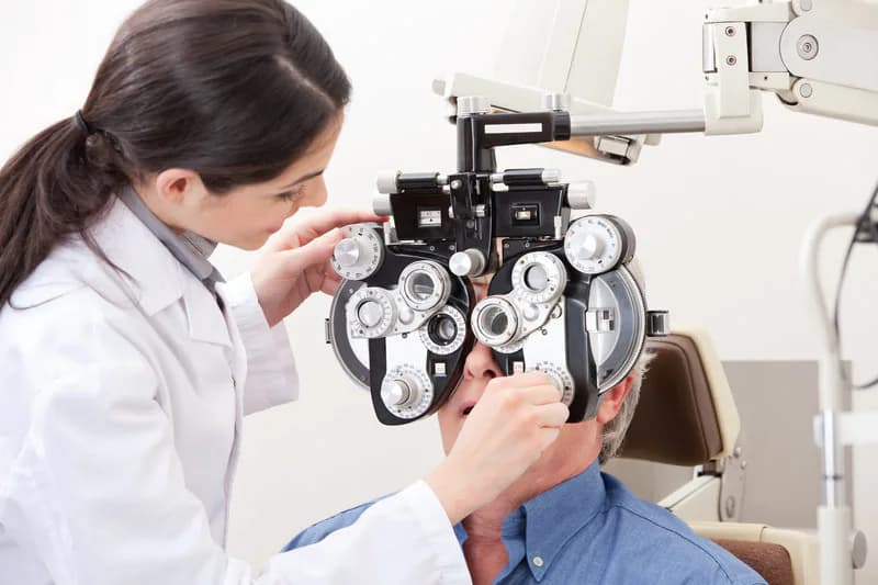 elderly patient sitting with their head resting in a slit lamp as a doctor examines them